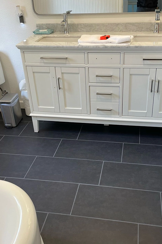 Modern Bathroom Vanity with White Cabinetry and Dark Tiled Flooring