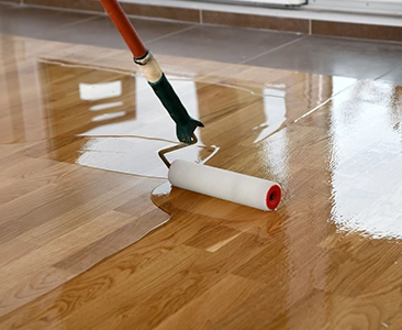 Paint Roller Applying Varnish to Wooden Floor During Home Remodeling Fairfield CA