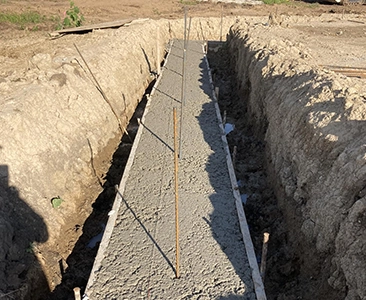 Freshly Poured Concrete Foundation in Earthy Trench for Custom Deck Construction
