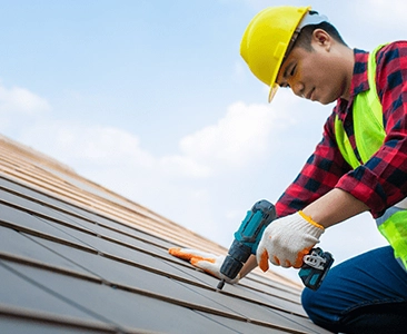Construction Worker In Hard Hat Installing Roof Tiles
