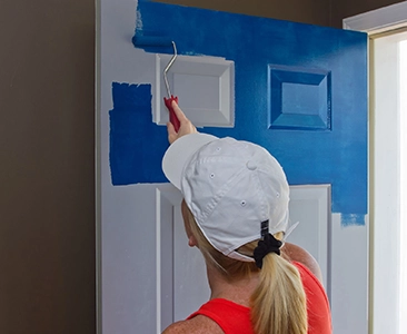 Person Painting Door with Blue Paint in Home Remodeling Project