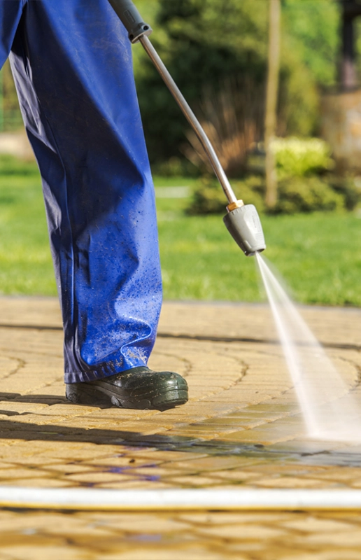 Person Pressure Washing a Patio with a High-Pressure Hose